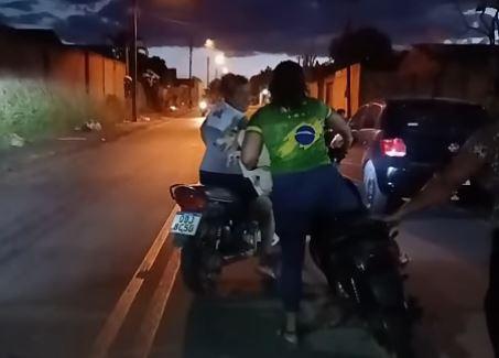 A imagem em destaque mostra a motociclista segurando o animal, enquanto uma mulher intervém no crime.