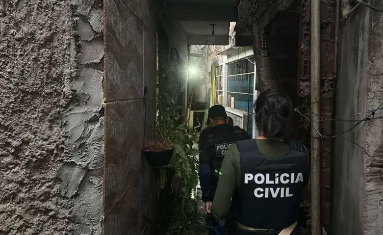 A imagem em destaque mostra policiais civis no cumprimento do mandado de prisão preventiva contra o suspeito.